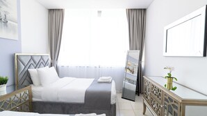 Een hotelkamer met een bed, een dressoir, een spiegel en een schilderij aan de muur.