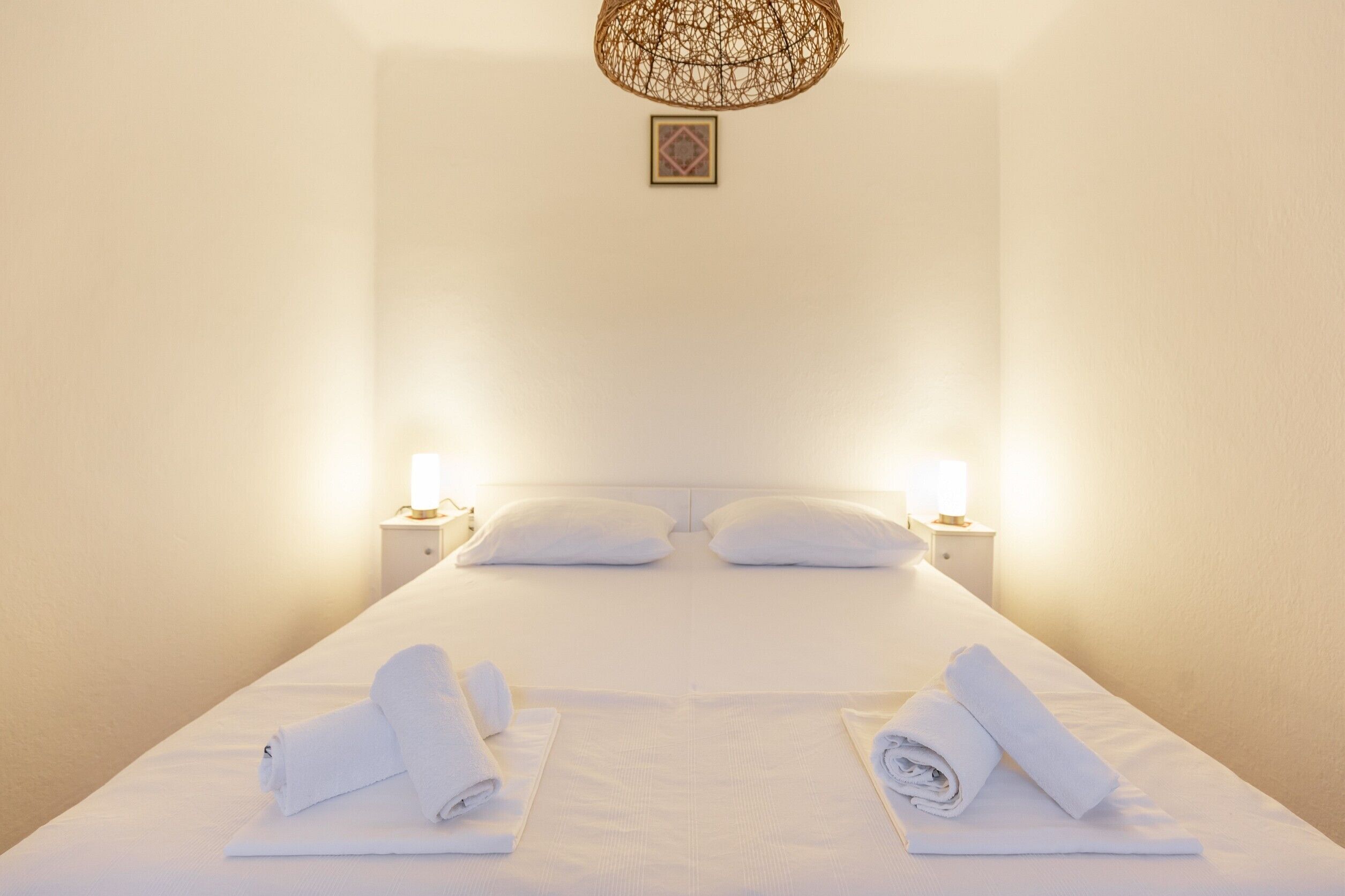 A hotel room with a large bed, two bedside lamps, and neatly folded towels on the bed.