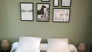 A neatly made bed with white pillows and a green bedspread, flanked by two wall-mounted lamps.