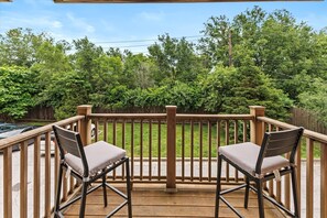 A wooden deck with two chairs and a view of a green backyard. - DT Indy near Convention Center (Indianapolis)
