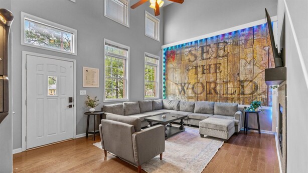 A living room with a sectional sofa, a coffee table, and a large wall mural.