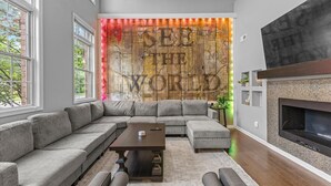 A modern living room with a sectional sofa, a coffee table, a fireplace, and a large wall mural.
