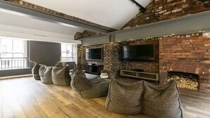 Un salon chaleureux avec une cheminée en briques, un téléviseur à écran plat et des fauteuils confortables en forme de poire.