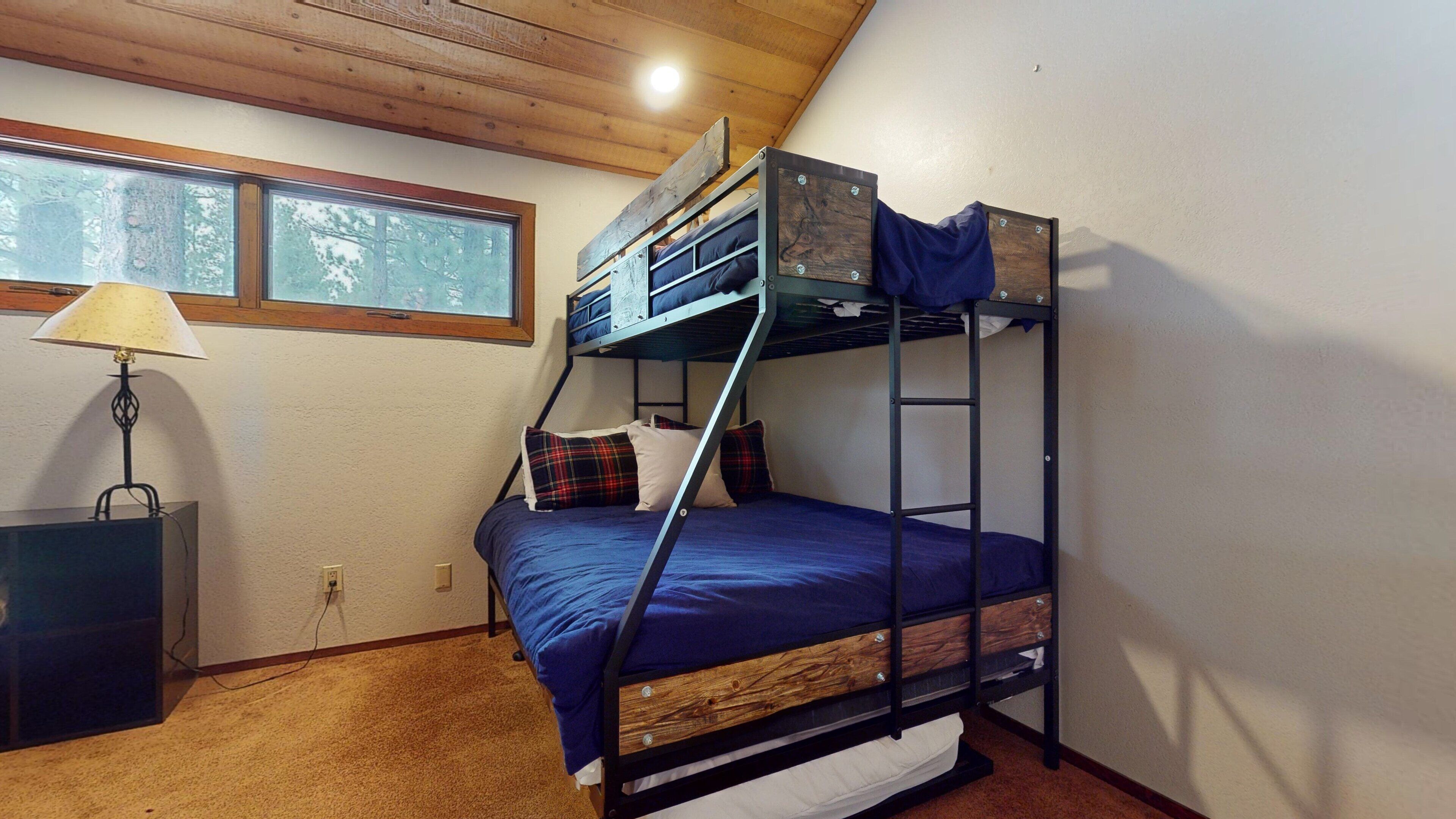 Habitación con literas, ventana, lámpara y escritorio.