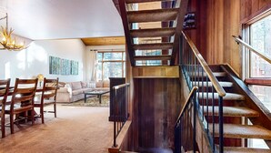 A spacious living area with a wooden staircase, a sofa, and a coffee table. - Woodlands #40 3 Bedroom Condo (Mammoth Lakes)