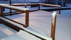 Een besneeuwde buitenruimte met een houten bank en een lantaarn.