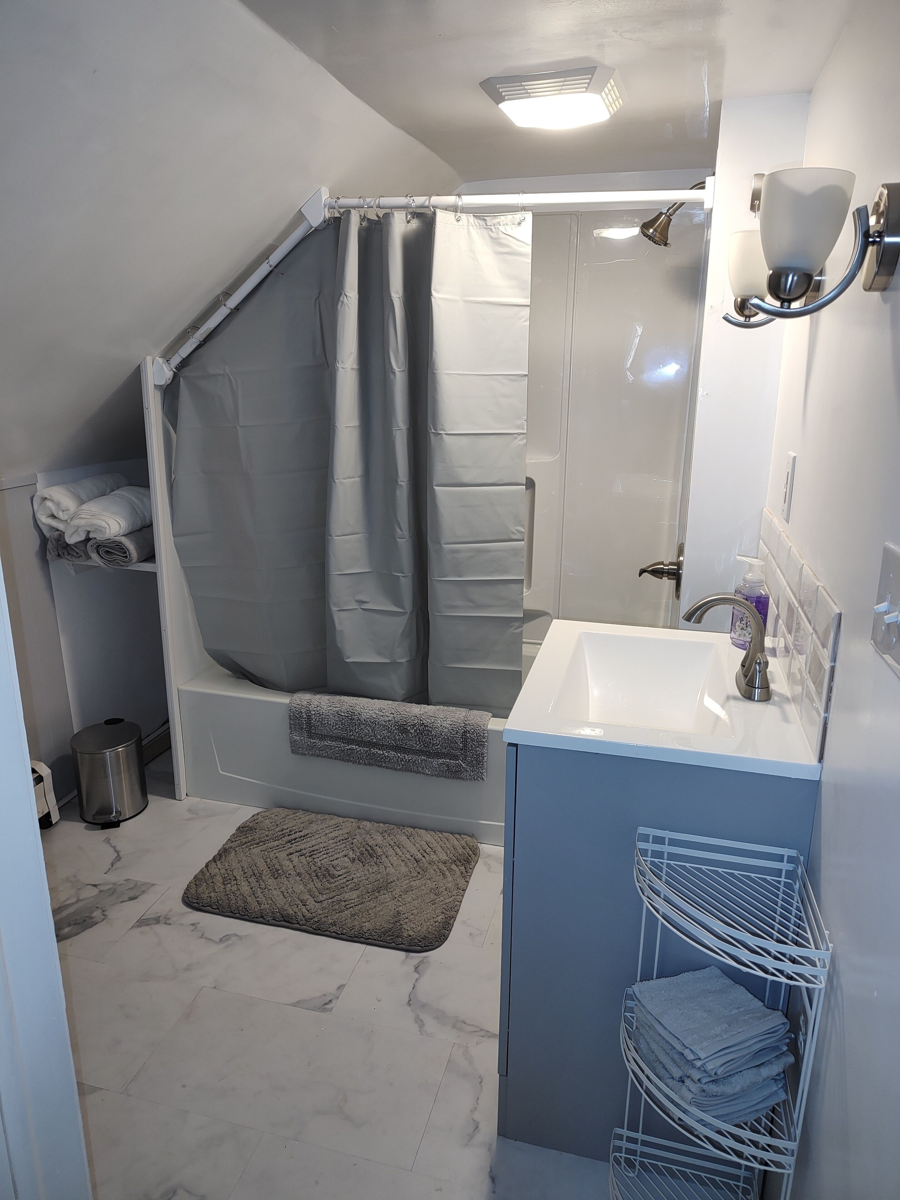 A modern bathroom with a shower, sink, and towel rack.
