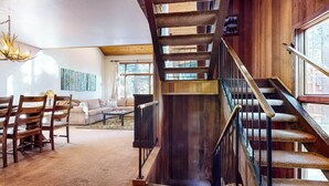 Un vaste espace de vie agrémenté d’un escalier en bois, d’un ensemble de canapés et d’un lustre.