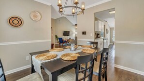 A dining area with a dark wooden table, woven placemats, and a chandelier.