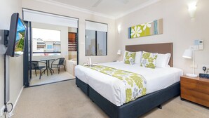 Una habitación de hotel con una cama, mesita de noche y vistas al exterior.