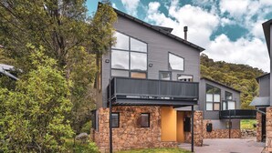 A modern two-story house with a stone facade, large windows, and a balcony.