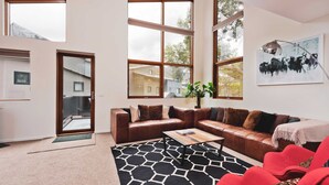 A modern living room with a brown leather sofa, a black and white patterned rug, and a red chair.