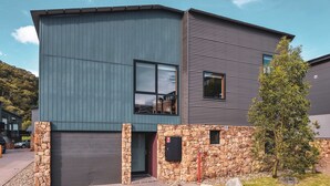 A modern two-story house with a stone foundation and a metal exterior. - Snow Stream 5 a 2 bedroom & loft apartment close to Friday Flat. (Thredbo)