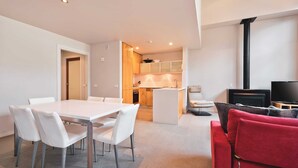 A modern apartment with a dining area, kitchen, living room, and a fireplace.