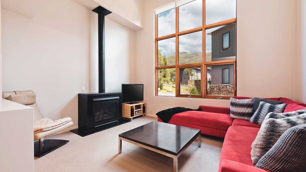 A modern living room with a fireplace, a red sofa, a coffee table, and a TV.