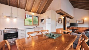 Een gezellige keuken met houten kastjes, een eettafel en een televisie in de woonkamer.