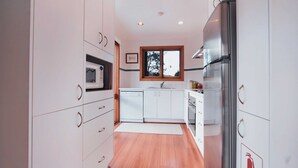 A modern kitchen with white cabinetry, a microwave, a sink, and a stainless steel refrigerator. - A stand alone 2 bedroom chalet with a large veranda to take in the mountain views (Thredbo)