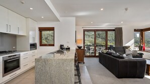 Una cocina moderna con encimeras de granito, electrodomésticos de acero inoxidable y una zona de comedor con sofá de cuero negro y mesa.