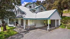 Une maison à deux étages dotée d’un porche couvert, de fondations en pierre et d’un toit à forte pente.