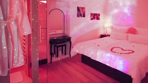 A bedroom with a bed, a dresser, a mirror, and a wall with a heart-shaped decoration. - Dream Room | Jacuzzi, Sauna, Waterbed (Forbach)
