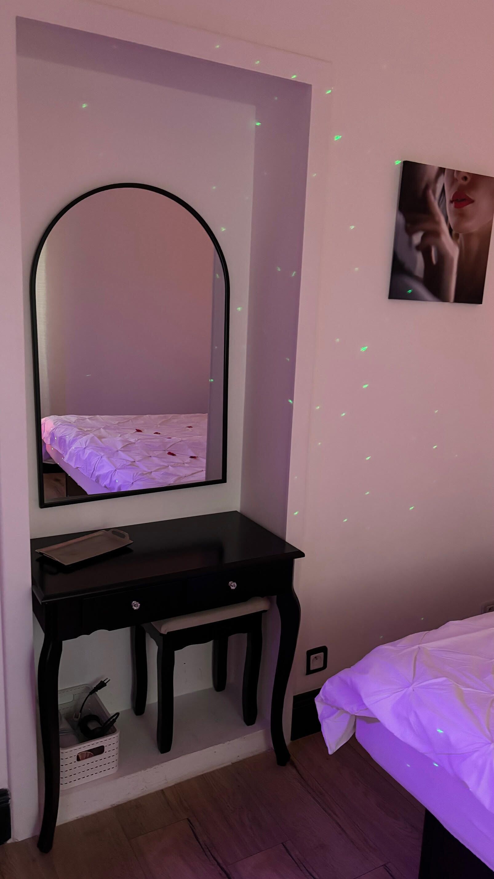 Quarto com penteadeira, cama e espelho fixado na parede.