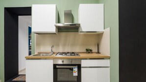 A compact kitchen with a gas stove, oven, and white cabinets. - Casa Papaccio Apartment (NAPOLI)
