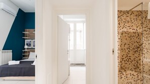 A modern bedroom with a bed, a wardrobe, and a bathroom with a shower. - Casa Papaccio Apartment (NAPOLI)
