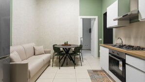 A compact kitchen with a dining area, a sofa, and a small table with chairs. - Casa Papaccio Apartment (NAPOLI)