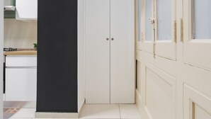 A narrow hallway with a white door, a black partition, and a kitchen area with a stove and cabinets. - Casa Papaccio Apartment (NAPOLI)