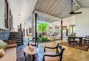 Un vaste espace intérieur doté d’un haut plafond, d’un escalier et d’un coin repas avec des tables et des chaises.