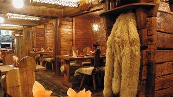 A rustic wooden interior with traditional furnishings and a fur coat hanging on the wall.