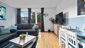 A modern living room with a grey sofa, a coffee table, and a dining area with white chairs. - Design luxury, fully equipped, 2min to Central Station (Duisburg)