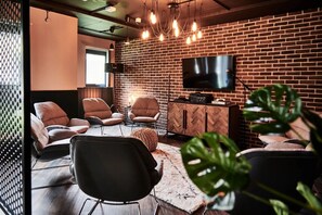 Un espace de détente moderne avec des fauteuils en cuir, un téléviseur et un mur en briques.