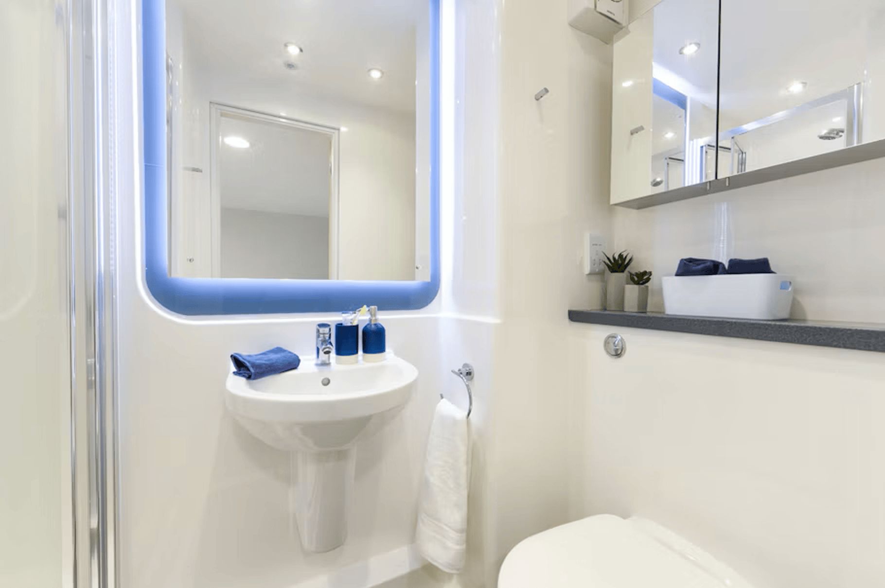 Un baño moderno con un lavamanos blanco, un espejo y un inodoro.