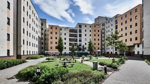 Une cour intérieure bordée de plusieurs immeubles d’appartements, avec des espaces de repos en plein air et de la verdure.