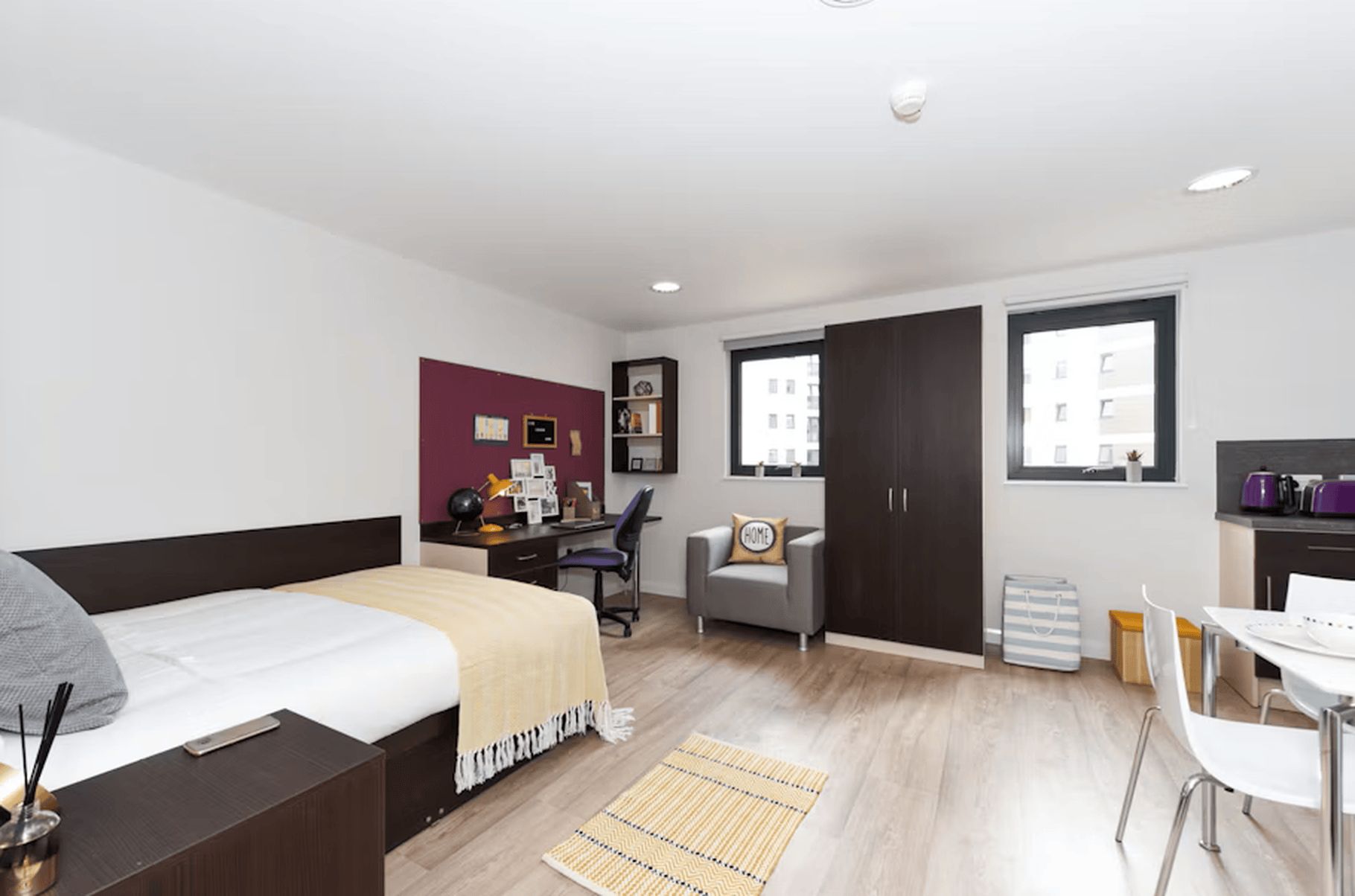 Een moderne slaapkamer met een bed, bureau, stoel en garderobe.