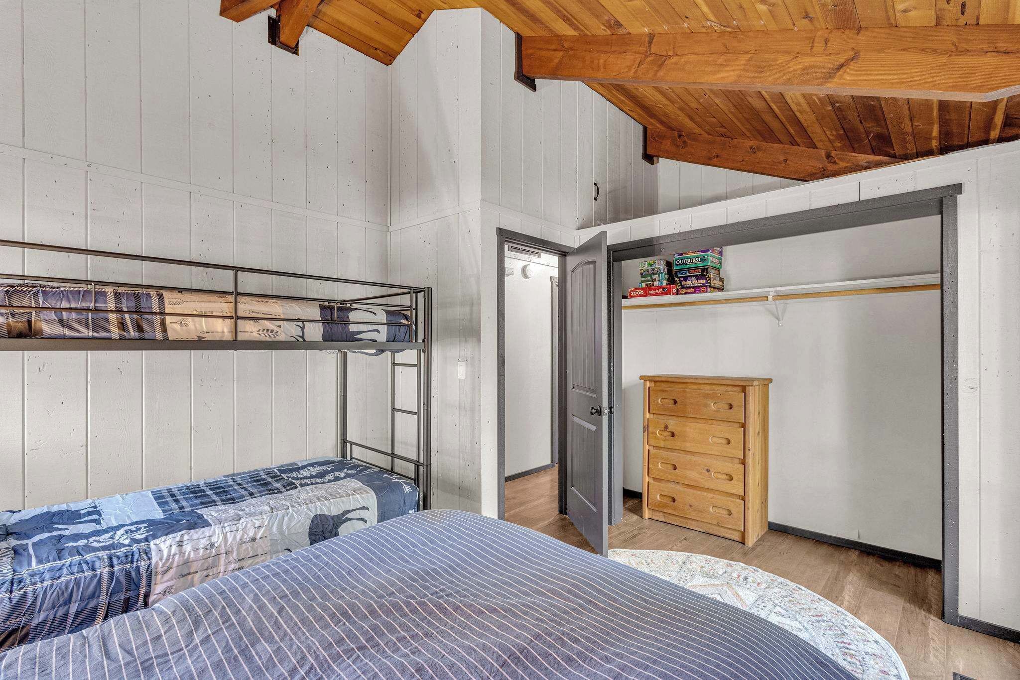 A bedroom with bunk beds, a wooden dresser, and a closet with shelves.