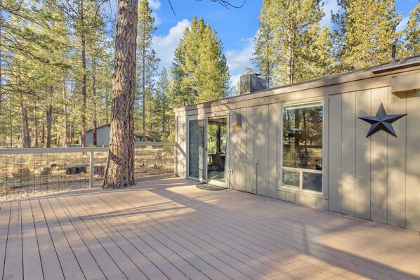 A modern cabin with a deck, surrounded by tall pine trees. - Private hot tub, dog friendly, great location (Sunriver)