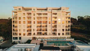 A multi-story hotel with balconies, a swimming pool, and a landscaped area.