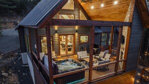 A wooden cabin with a hot tub and outdoor seating area. - Luxury Forest Escape | NEW POOL, Loft, Swings Fire Pit &  gorgeous nature views (Broken Bow)