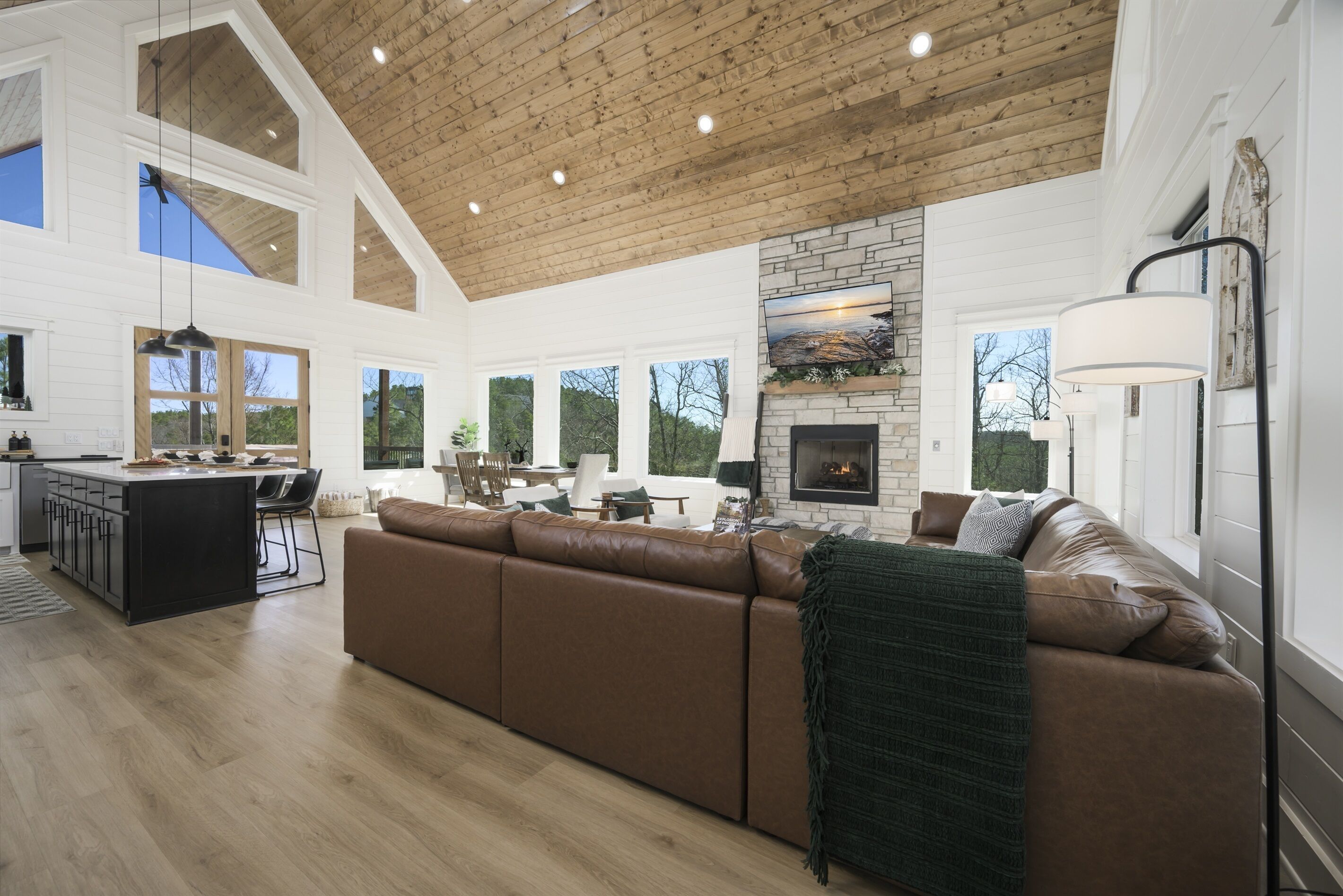 A spacious living room with a large brown leather sofa, a fireplace, and a kitchen area with a bar.