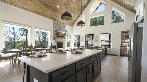 A spacious kitchen with a large island, wooden ceiling, and large windows offering views of the outdoors. - Luxury Forest Escape | NEW POOL, Loft, Swings Fire Pit &  gorgeous nature views (Broken Bow)