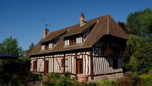 A traditional half-timbered house with a steeply pitched roof, multiple chimneys, and a small balcony. - La chasse - a beautiful cottage between coast and countryside (Anglesqueville-la-Bras-Long)