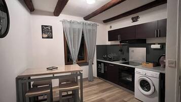 Una cocina compacta con zona de comedor, suelo de madera y lavadora.