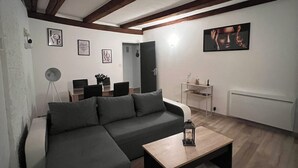 A modern living room with a sectional sofa, a coffee table, and a dining area with a small table and chairs.