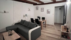 A modern living room with a sectional sofa, a small table, and a dining area with chairs.