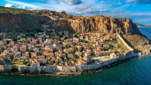 Une ville côtière dotée de bâtiments historiques, d’une muraille fortifiée et offrant une vue dégagée sur la mer.