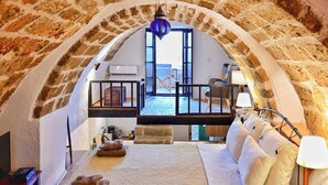 Ein gemütliches Schlafzimmer mit Steinwänden, einem Bett, Kissen und einer Lampe.