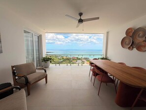 Un balcon avec vue sur l’océan et un coin repas comprenant une table et des chaises.