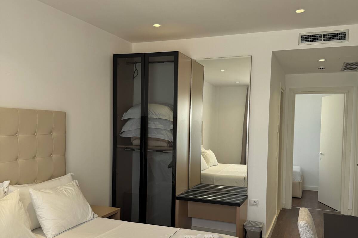 Ett hotellrum med en stor säng, en garderob, ett skrivbord och en stol.